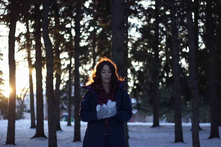 woman holding snow near trees during sunset, woman standing on snowy ground in the middle of forest HD wallpaper