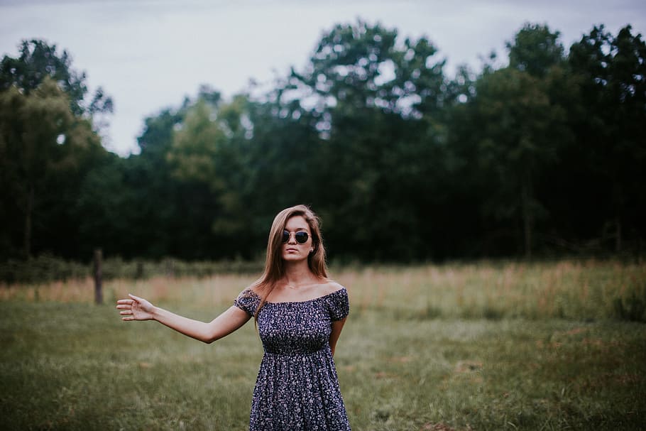selective focus photo of woman standing on grass field, woman standing wearing blue dress near green field grass during daytime HD wallpaper