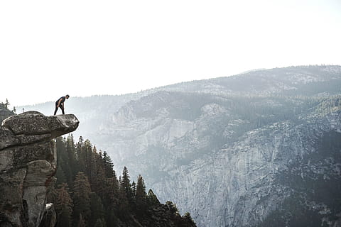 man standing on cliff, man wearing black shirt standing on cliff while looking forest HD wallpaper