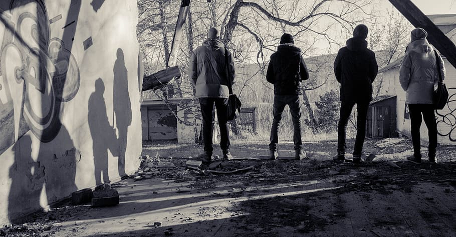 grayscale photo of four men standing near wall facing trees HD wallpaper