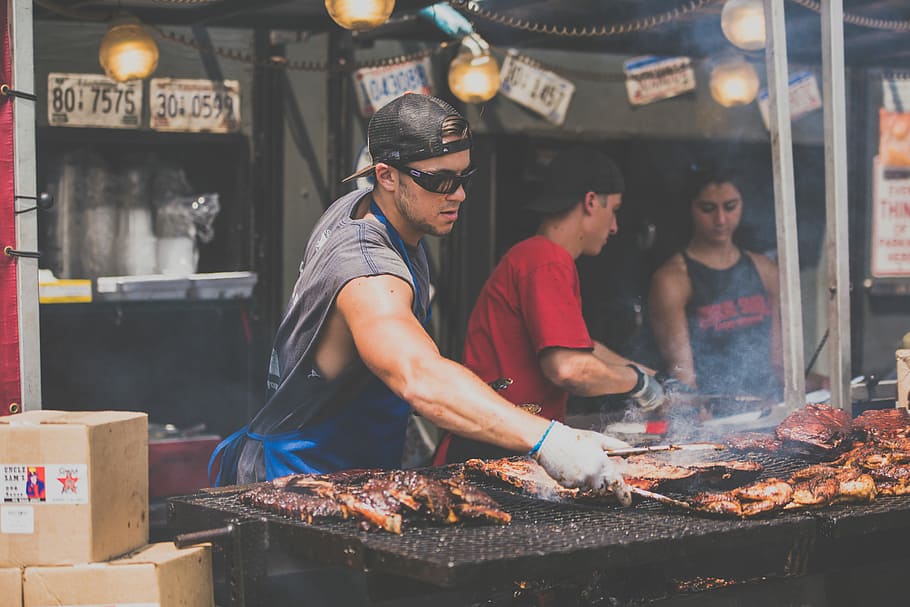 man standing infront of grill while holding tong, man grilling meat