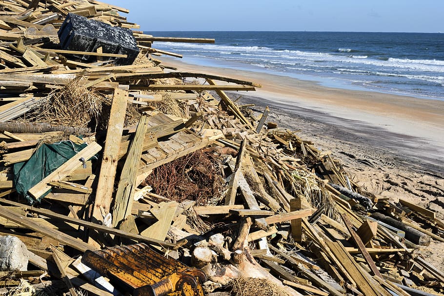 stacked lumbers near body of water, hurricane matthew, damage