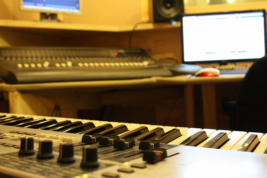 gray electric keyboard near black audio mixer, recording studio