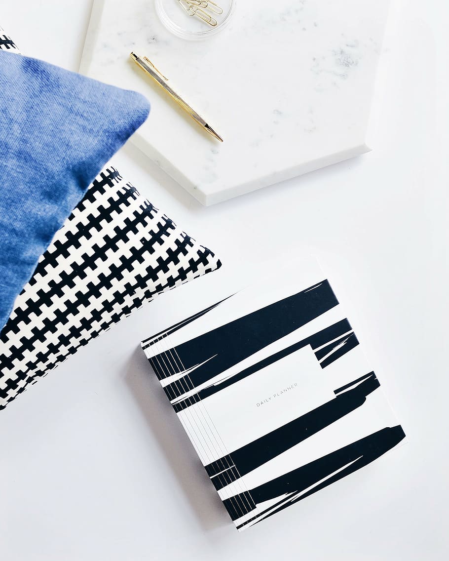 black and white notepad and gold-colored click pen on flat-lay photography HD wallpaper