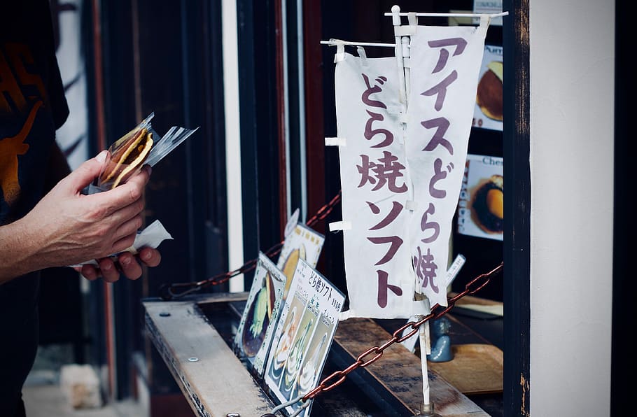 photo of person holding food, white and brown flag, sign, writing HD wallpaper