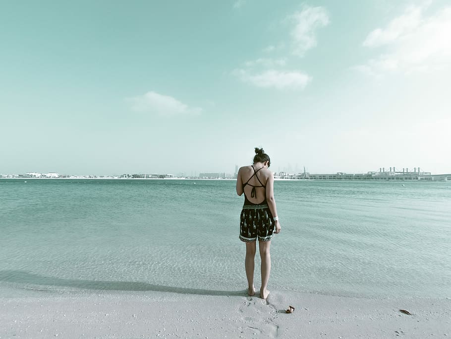 woman in black outfit standing on beach sand, woman standing on shore under cloudy sky HD wallpaper