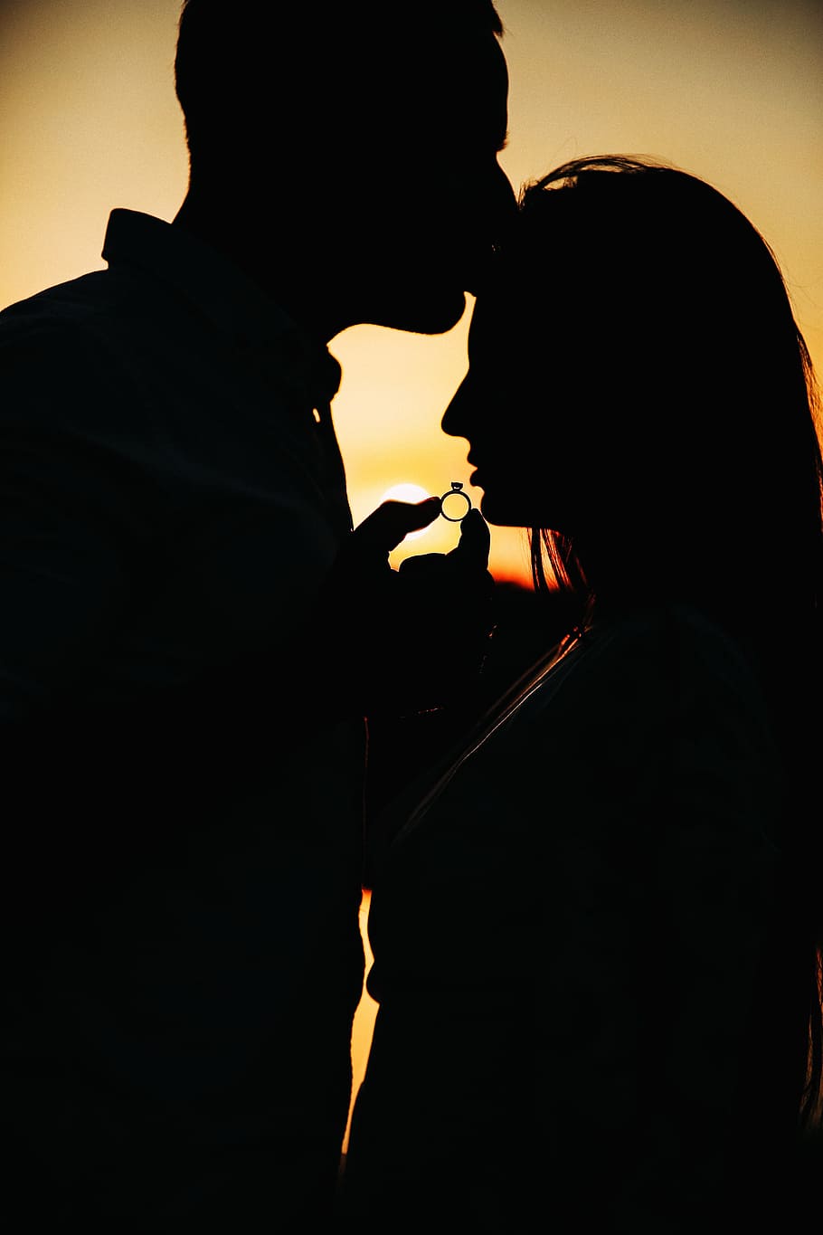 silhouette of couple holding ring during golden hour, portrait