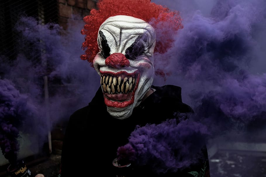 monster clown surrounding fog, person with clown mask holding purple smoke can