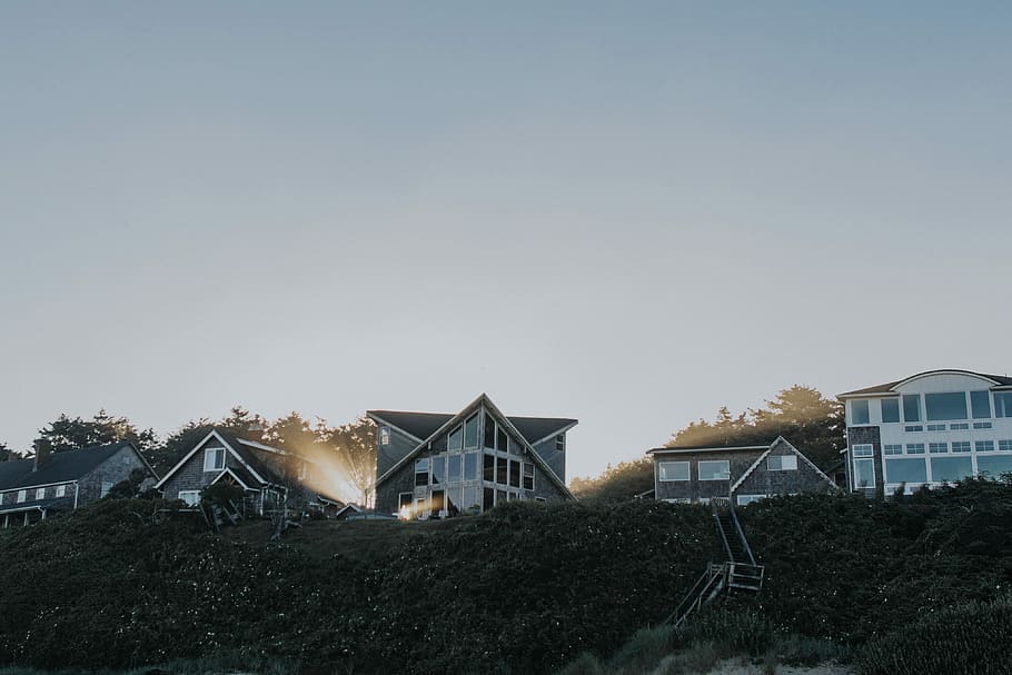 white curtain wall house near green bush, gray buildings in high ground at daytime HD wallpaper