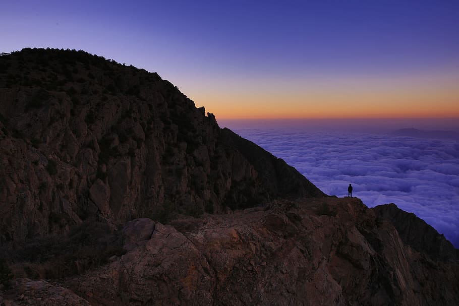 person standing on mountain in front of body of water, person on hill watching the clouds HD wallpaper