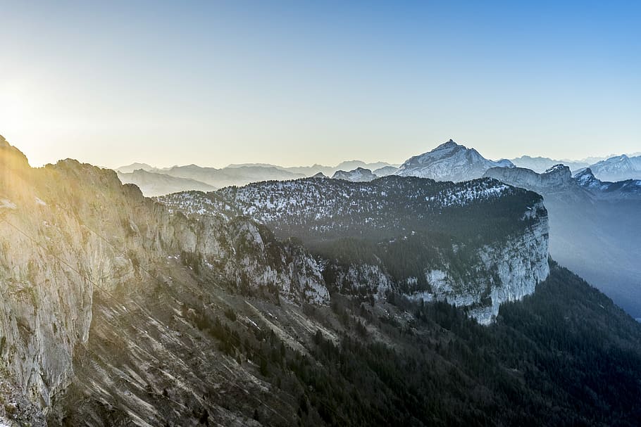 trees on cliff under clear sky, landscape photography of rocky mountains under blue and yellow sky during daytime HD wallpaper