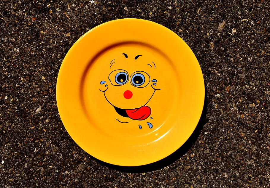 round yellow face print ceramic plate on top of black granite surface HD wallpaper