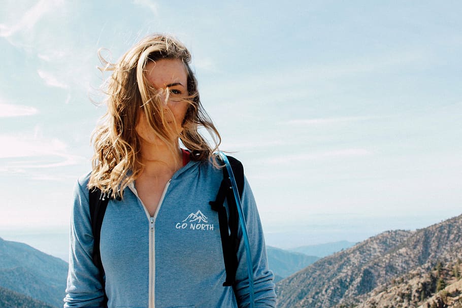 woman wearing blue Go North zip-up jacket standing on peak of a mountain during day HD wallpaper