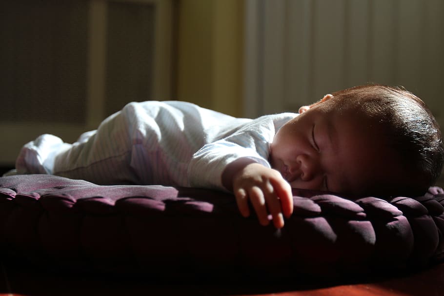 baby wearing white footie pajama lying on brown pillow, sleeping HD wallpaper