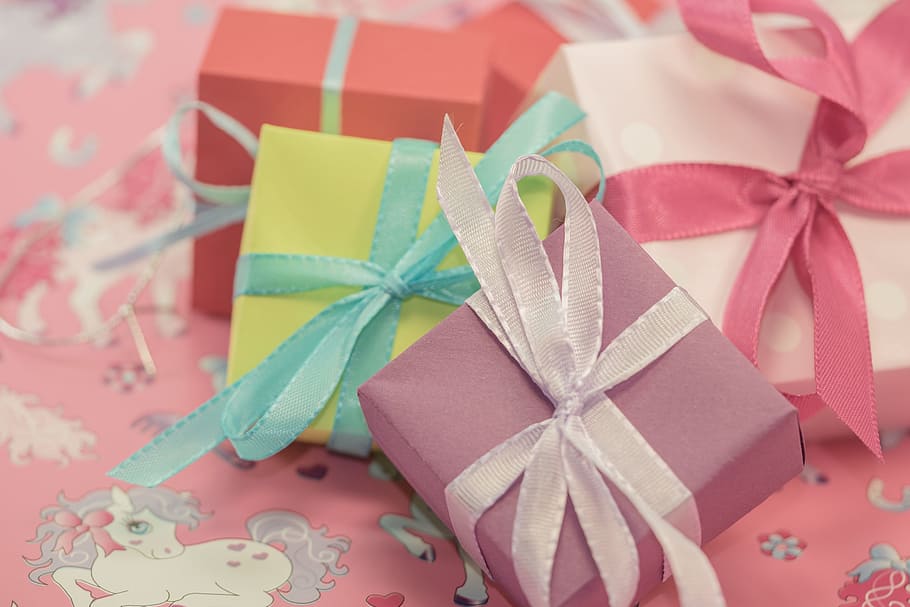 four assorted-color gift boxes on white and pink pony print fabric sheet HD wallpaper