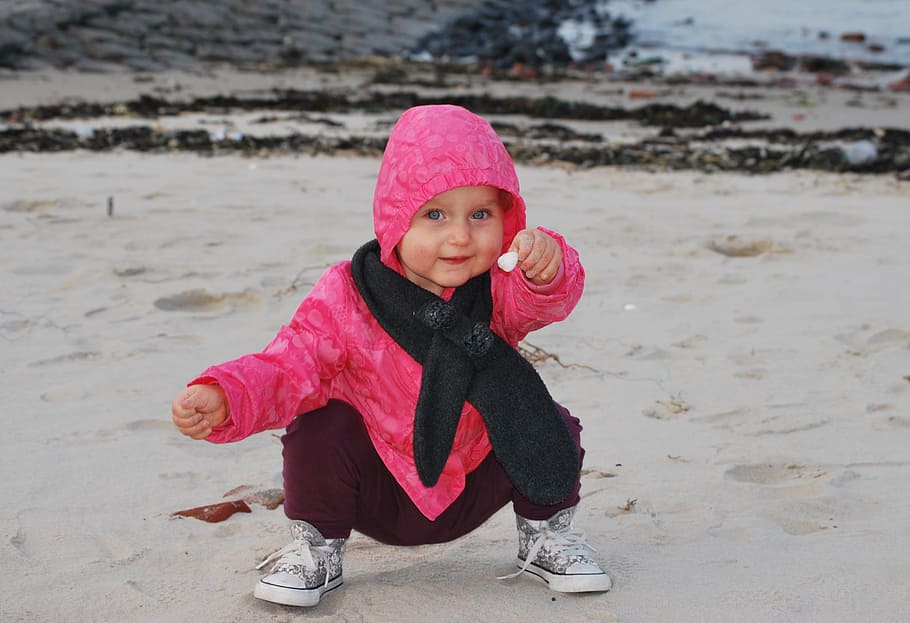 girl squats on grey sand holding flower, child, beach, shell HD wallpaper