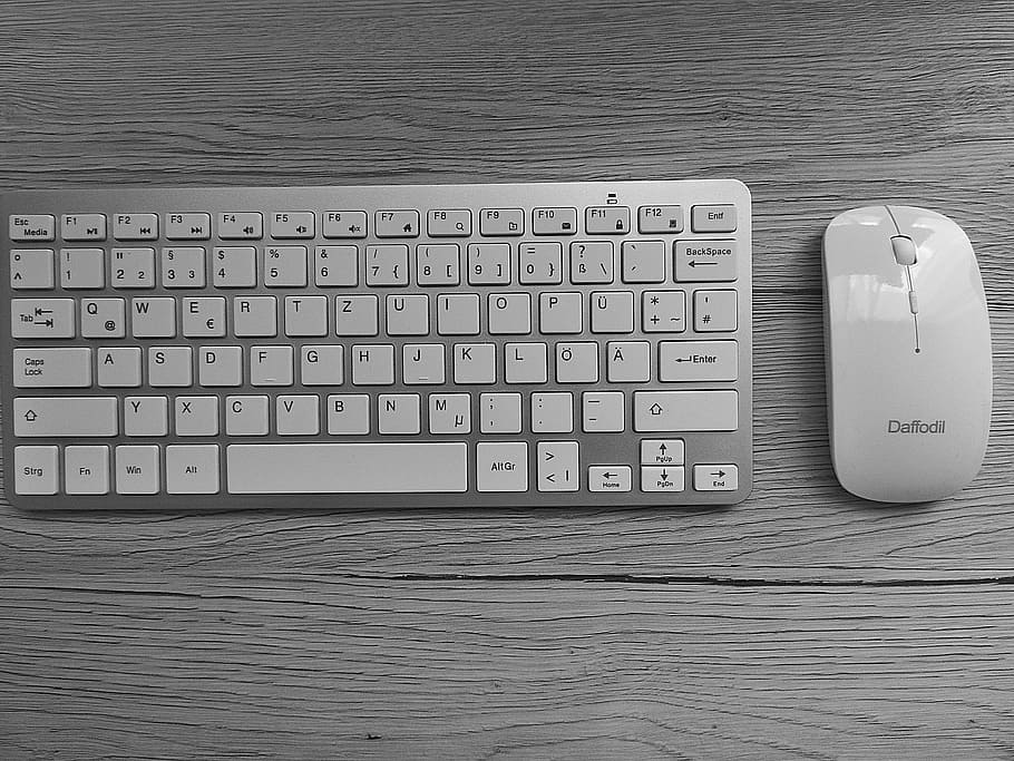 silver wireless keyboard beside white wireless mouse both on brown wooden panel HD wallpaper