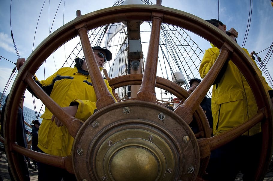 two men wearing yellow overalls near ship wheel at daytime HD wallpaper