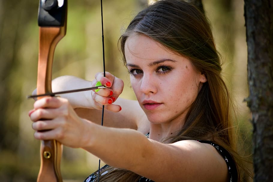 selective focus photography of woman in black top aiming her bow HD wallpaper