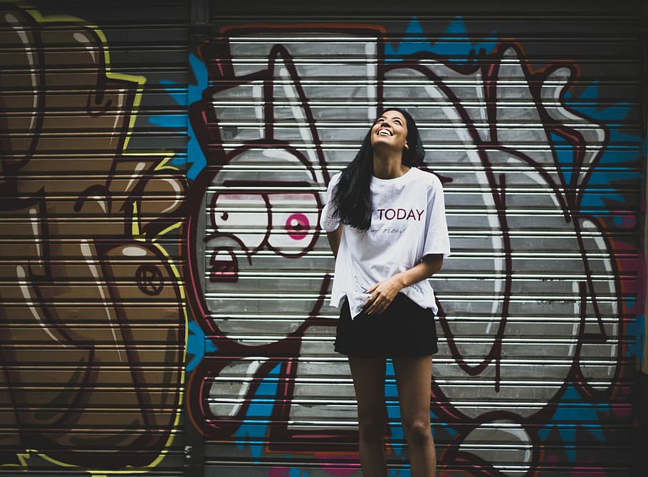 woman standing beside graffiti wall taken at daytime, woman looking up while standing against wall HD wallpaper