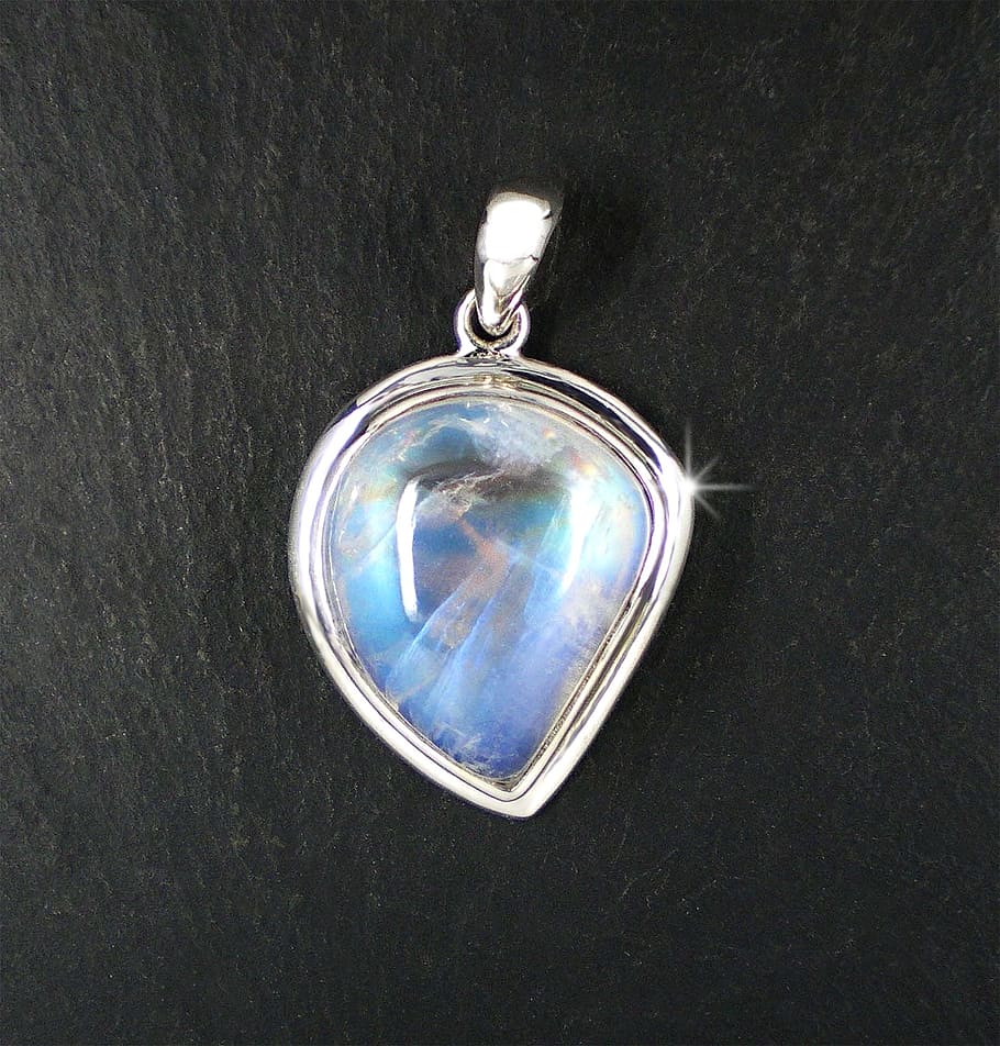 silver-colored pendant with clear gemstone, moonstone, ground