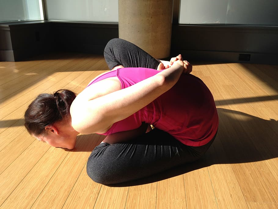 woman wearing pink sleeveless shirt kissing the floor, yoga, flexibility