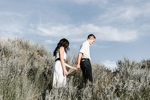 couple walks of grassy field, man and woman holding hands while walking on grass field at day time HD wallpaper