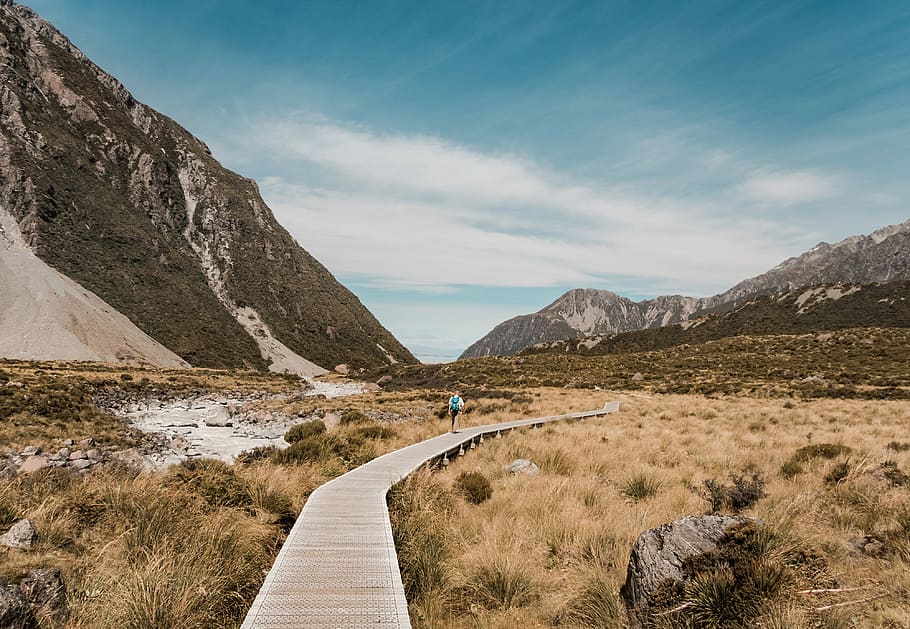 person on beige bridge at mountain valley, person walking on desert HD wallpaper