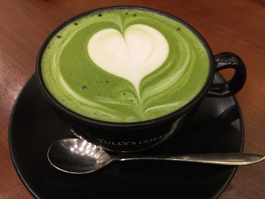 black ceramic teacup and gray metal spoon with cappuccino, matcha green tea