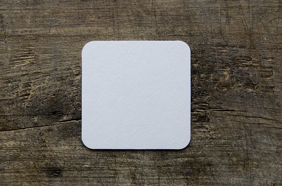 square white card on brown wood board panel, beer coasters, blank