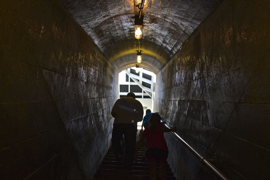 man and child passing through tunnel, man and girl climbing on stairs HD wallpaper