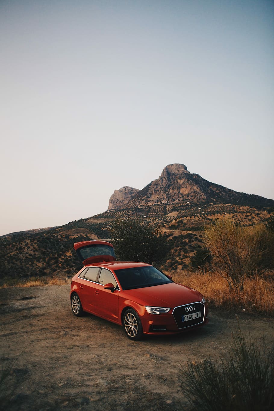 red Audi 5-door hatchback near mountain, red Audi 5-door hatchback parked at near grass field and mountain during daytime HD wallpaper