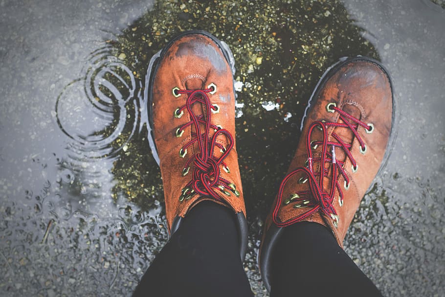 person wearing brown lace-up boots standing on wet ground, person standing on wet floor