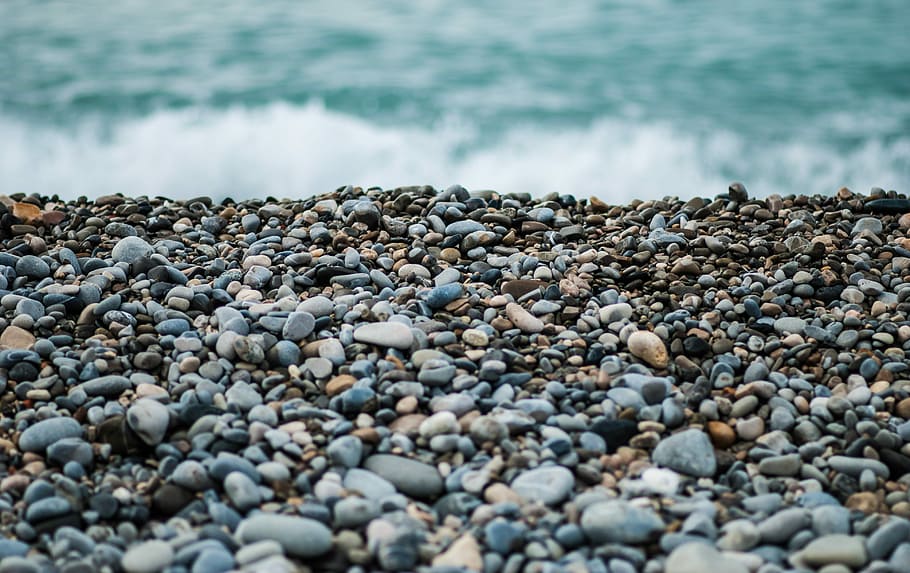 gray and black stones near sea at dayime, gray pebbles on shore during daytime HD wallpaper