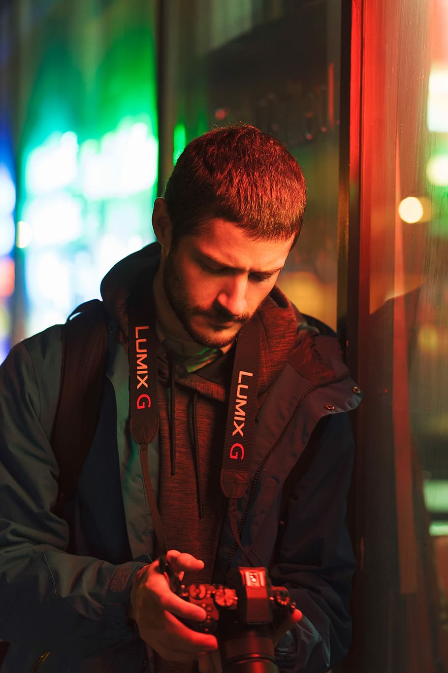 man in black jacket holding Lumix G camera, man leaning on wall holding DSLR camera, HD wallpaper