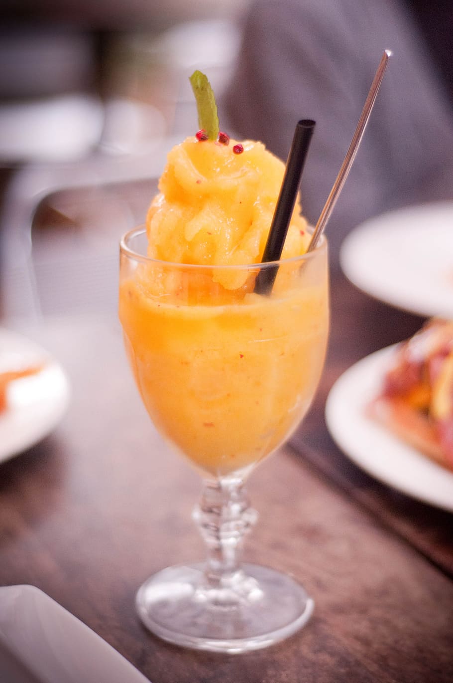clear footed drinking glass filled with orange liquid on table HD wallpaper