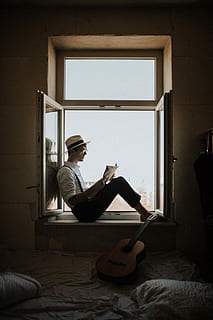 man sitting on window while reading, man reading book while sitting on window HD wallpaper