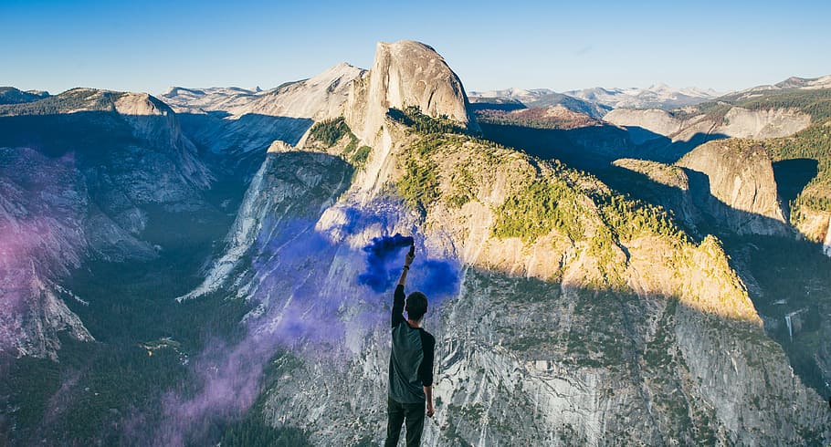 person wearing gray shirt facing gray mountain, man standing on high ground facing gray mountains at daytime HD wallpaper