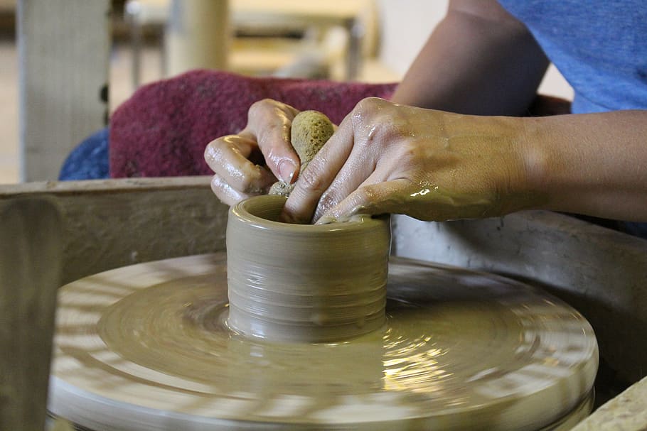 person sitting down molding clay, potter, hands, wheel, ceramic
