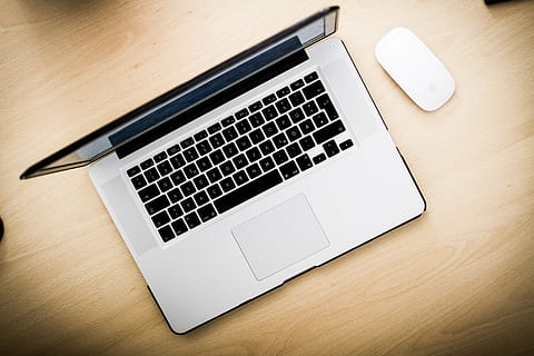 black and gray laptop computer beside white Apple Mighty Mouse on brown wooden surface HD wallpaper