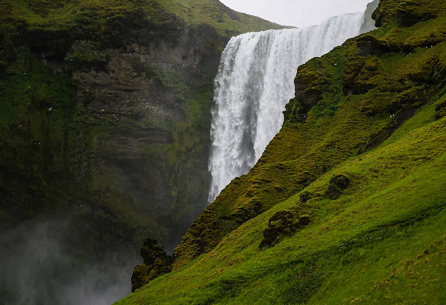 green grass-covered mountain beside waterfalls, Skogafoss, Ice Land HD wallpaper