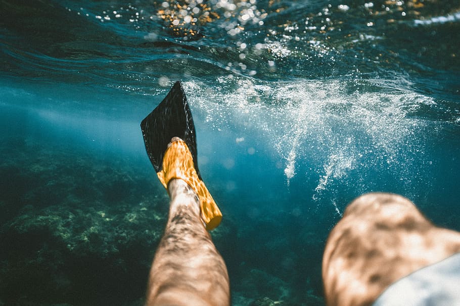 closeup photo of person diving underwater, person wearing black and yellow flippers underwater HD wallpaper