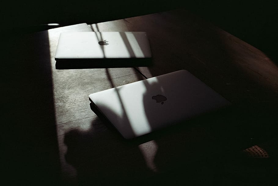 two silver MacBooks on table, two white MacBooks on brown table HD wallpaper