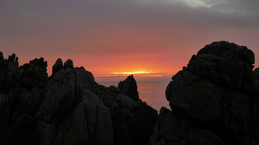 brown cliff near body of water at sunset, silhouette of rocky mountain near seashore HD wallpaper