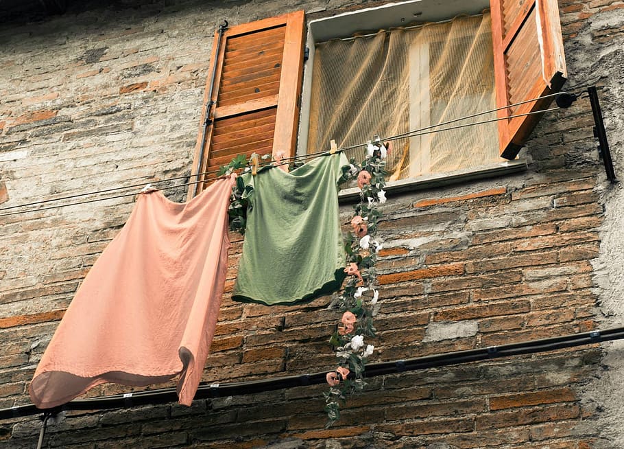 two pink and green shirt and skirts hanging on clothes line, window