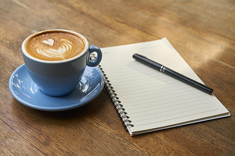 black and white electronic device, cup of espresso on saucer beside spiral note HD wallpaper