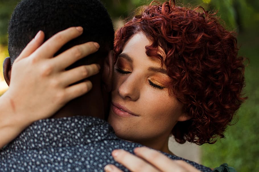 man and woman hugging each other during day time, red hair, eyes closed