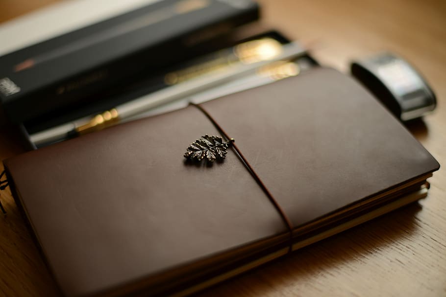 selective focus photography of brown planner, traveler's notebook HD wallpaper