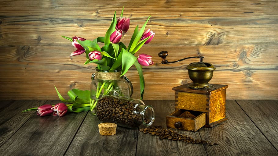 pink flowers beside brown wooden manual coffee grinder, grain coffee