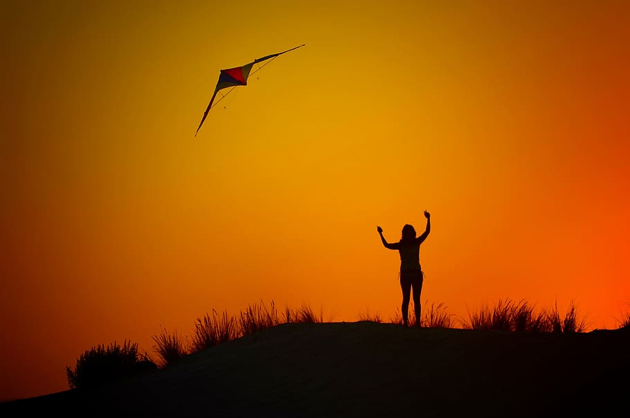 silhouette of woman flying kite, backlight, dusk, beach, sunset
